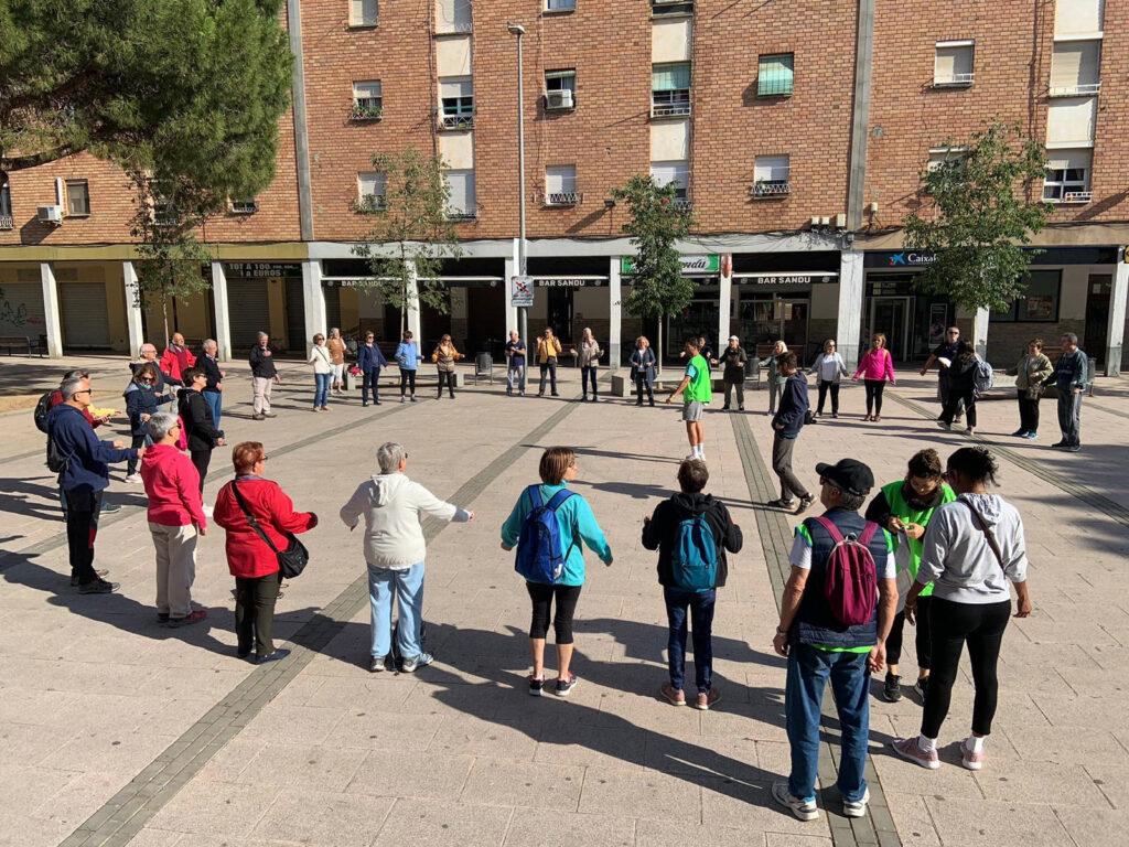 Gent fent rotllana en una plaça.