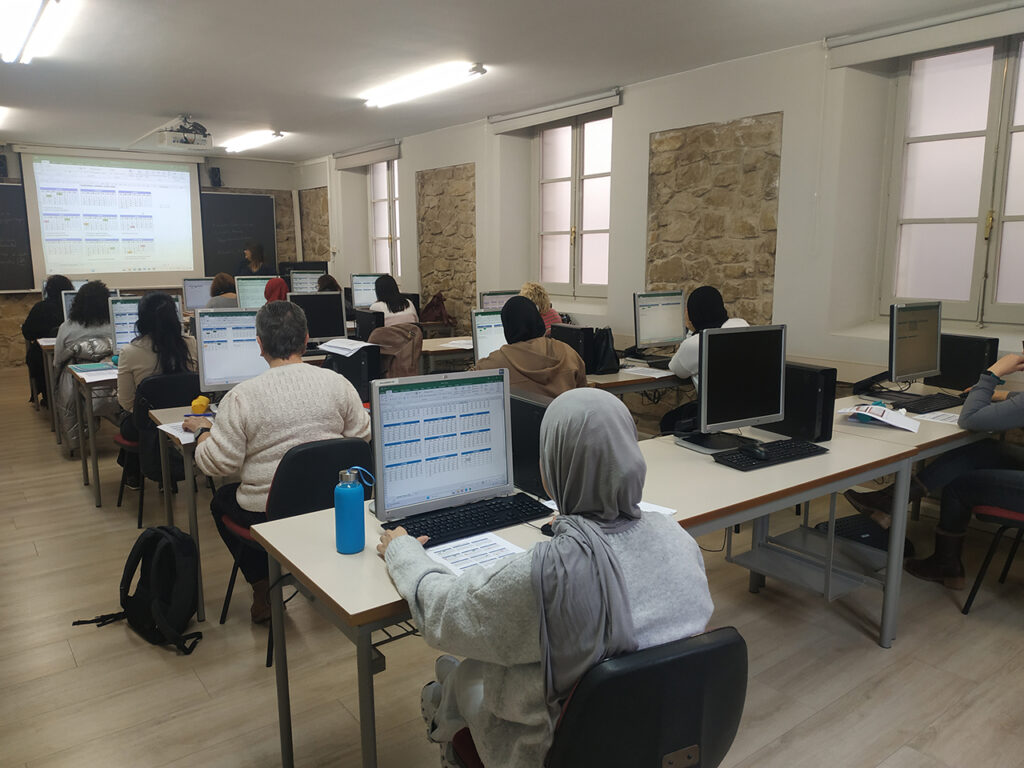 Grup de dones fent formació en una aula d'informàtica.
